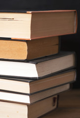 Close-up of used books stacked on black background. Vertical shoot.