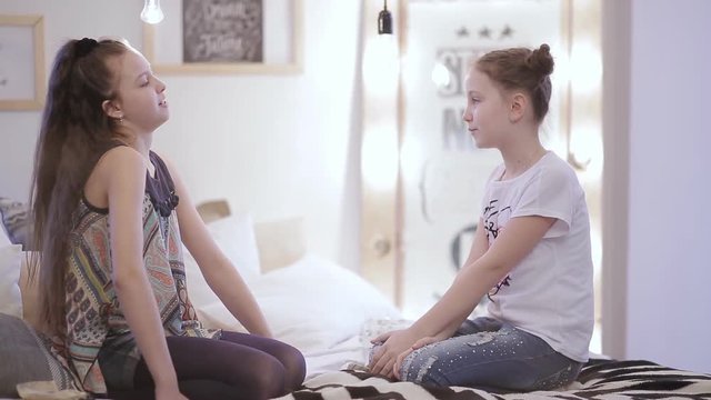 Little Girlfriends are playing sitting by the window.