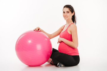 Young beautiful pregnant woman doing exercises with fitball