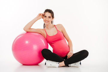 Beautiful young pregnant woman sitting with fitball