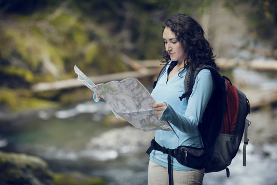 Young woman checking map by stream