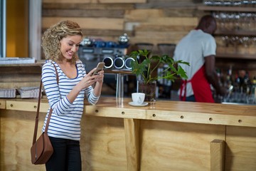 Woman using mobile phone at counter