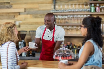 Waiter serving coffee to female customer