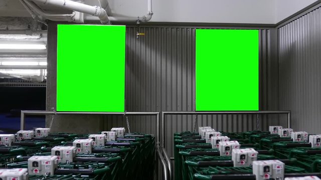 Row of empty shopping carts with two green screen boards