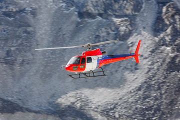 The helicopter flies over the Khumbu glacier on the background of the Lhotse peak near EBC -...