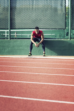 Sportsman resting by running track on stadium