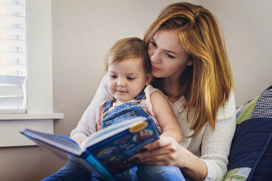 Mother and daughter sitting together and reading book