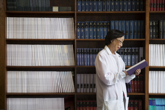 Female scientist reading book in library