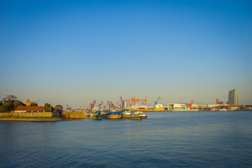Naklejka premium SHANGHAI, CHINA: Shanghai riverbank, industrial boats and some port facilities lying waterfront, beautiful blue sky
