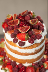 Naked cake on the gray background. Cake with fresh berries and white cream close up. holiday concept.