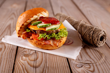Delicious beef burgers with lettuce served on pieces of parchment paper on rustic wooden table