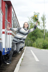 Girl teenager with flowers on the running board of a train