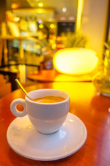 SHANGHAI, CHINA: Small white espresso cup sitting on saucer with coffee inside, cafeteria environment