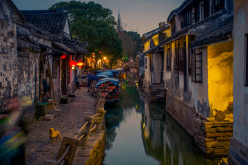 Fototapeta na wymiar SHANGHAI, CHINA: Beautiful evening light creates magic mood inside Zhouzhuang water town, ancient city district with channels and old buildings, charming popular tourist area