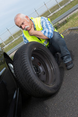 Obraz na płótnie Canvas discouraged retired man unable to change car tyre
