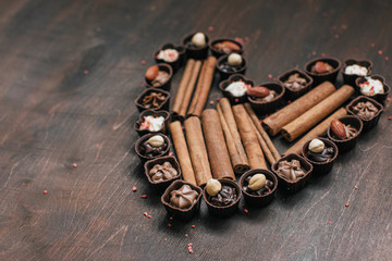 heart with chocolate candy and cinnamon on vintage rustic wooden background. Love concept