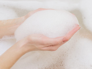 Beautiful female hands in white soap.
