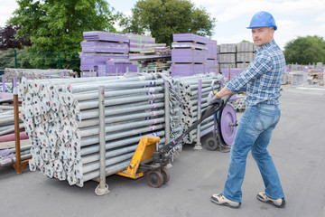 Worker moving pallet of scaffold poles
