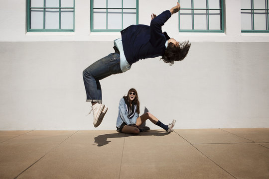Young man doing somersault,  friend watching