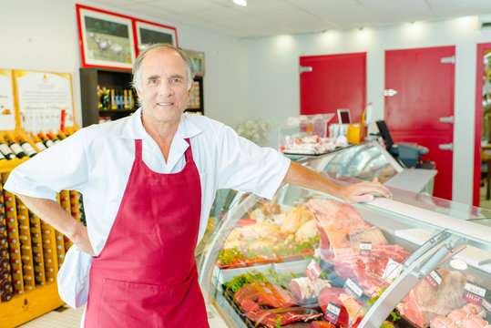Proprietor of Deli leaning on chilled counter