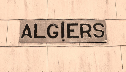 Weathered sign for the Algiers neighborhood of New Orleans in sepia