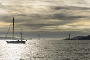 A cloudy sunset over the San Francisco bay seen from a boat on the water. Views of the city and golden gate bridge