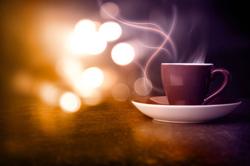 Steaming cup of coffee on table and black background