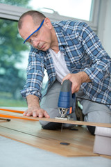 carpenter cutting laminated planks for layered parquet using bandsaw
