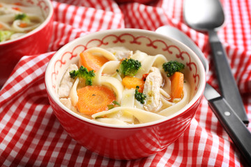 Chicken noodle soup in bowl on checkered napkin