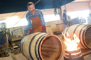 wood barrels production cooper using hammer and tools in workshop - obrazy, fototapety, plakaty