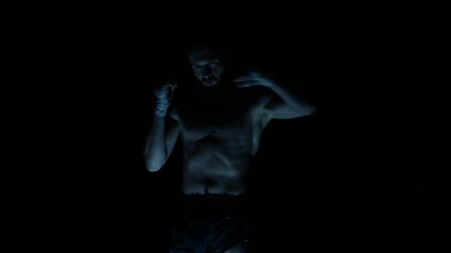 Professional fighter shadowboxing with fire and sparks on background