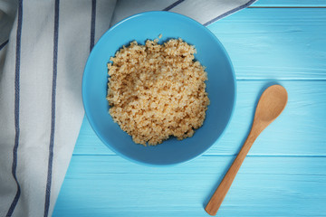 Top view of blue plate with sprouted organic white quinoa grains on wooden background