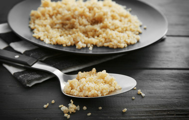 Spoon with boiled sprouted organic quinoa grains on wooden background