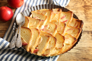 Tasty bread pudding with apples in baking dish on kitchen table