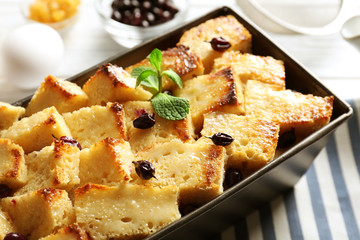 Delicious bread pudding with currant in baking dish on kitchen table