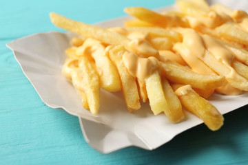 Tasty cheese fries on blue wooden table