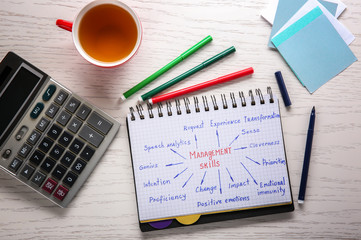 Notebook with written list of MANAGEMENT SKILLS on wooden background