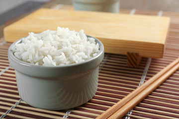 Bowl of rice and chopsticks on bamboo mat