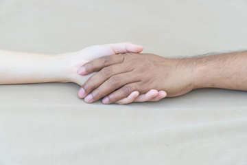 Male and female hands on brown fabric background