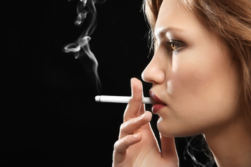 Obraz premium Portrait of beautiful woman with cigarette on black background