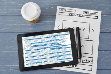 Programmer concept. Digital tablet, flowchart and cup of coffee on grey wooden background