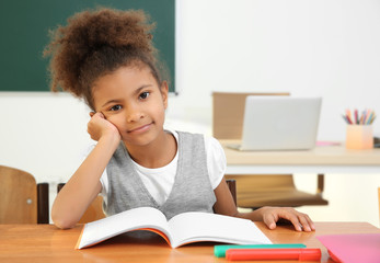 Portrait of beautiful African elementary schoolgirl sitting in classroom