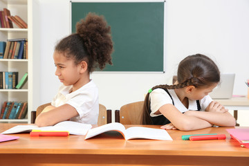 Beautiful quarreled elementary schoolgirls sitting in classroom