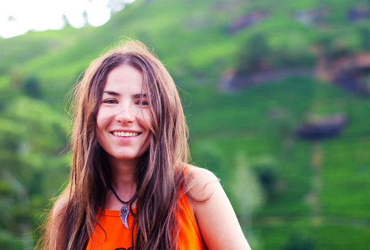 Beautiful girl without makeup with long hair smiles against the background of mountains
