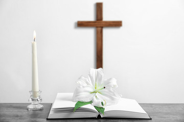 Composition with Holy Bible, lily, candle and cross on light background