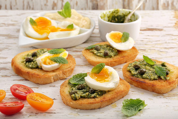 Fresh sandwich with pesto and egg on wooden background