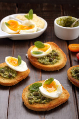 Fresh sandwich with pesto and egg on wooden background