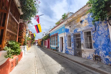Fototapeten CARTAGENA, COLOMBIA - MAY 23: Flags blow in the breeze on a colorfully painted street in Cartagena, Colombia on May 23, 2016. © Danaan