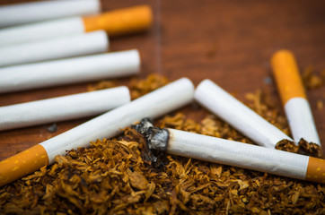 Closeup cigarettes and tobacco lying around on wooden surface, anti smoking concept