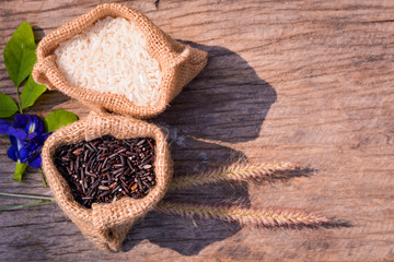 Black rice and Raw grain white rice in burlap bag on wood background,Jasmine rice,